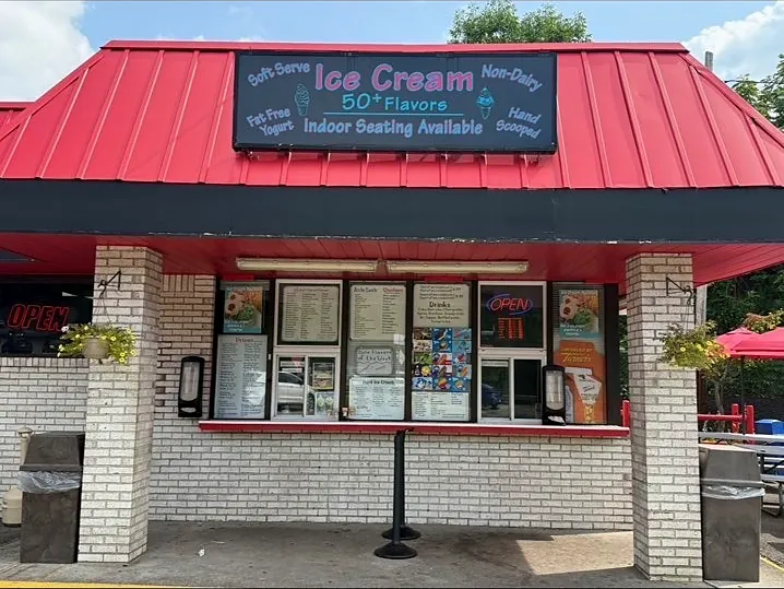 Charlie's Ice Cream from the parking lot: a red-roofed walk-up stand with its menu boards lit and the OPEN sign on